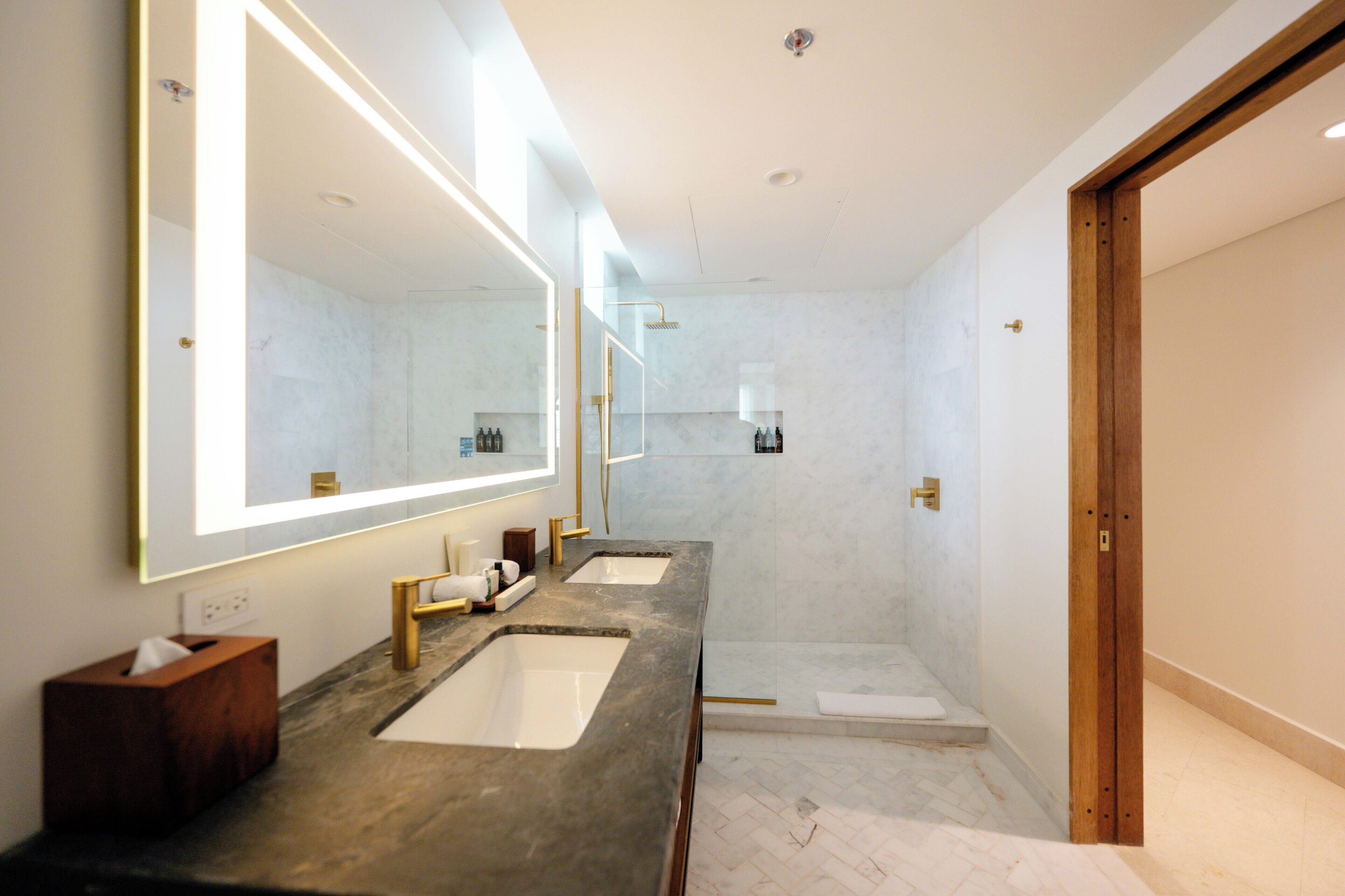 A modern bathroom with two sinks, a large mirror, and a shower area.