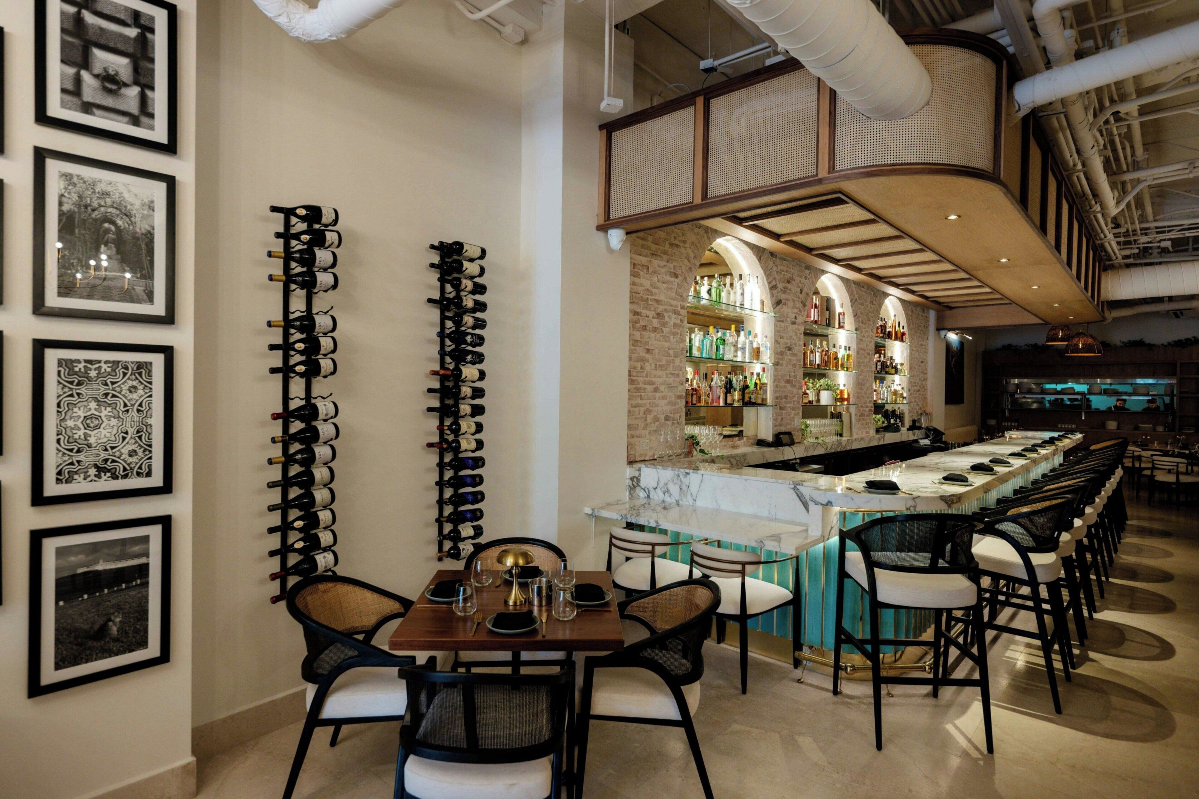 A bar area with a long counter, multiple bar stools, and a seating area with a table and chairs.