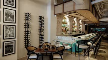 A bar area with a long counter, multiple bar stools, and a seating area with a table and chairs.