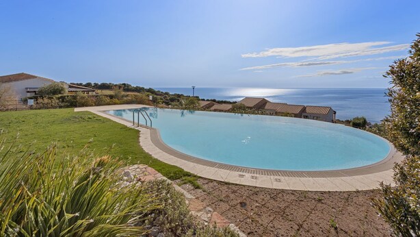 A large, curved swimming pool with a clear view of the ocean in the background. - Casa Margarita with seaview and pool (Tertenia)
