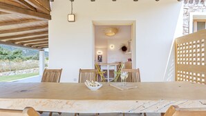 A wooden dining table with chairs, a bowl of bread, and a glass of wine. - Casa Margarita with seaview and pool (Tertenia)