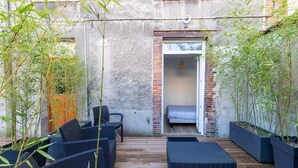 An outdoor seating area with wicker furniture and bamboo plants.