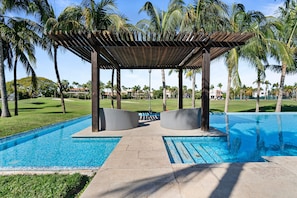 A pool area with a pergola, lounge chairs, and palm trees. - Tranquil Peninsula Golf 3BR Retreat (Nuevo Nayarit)