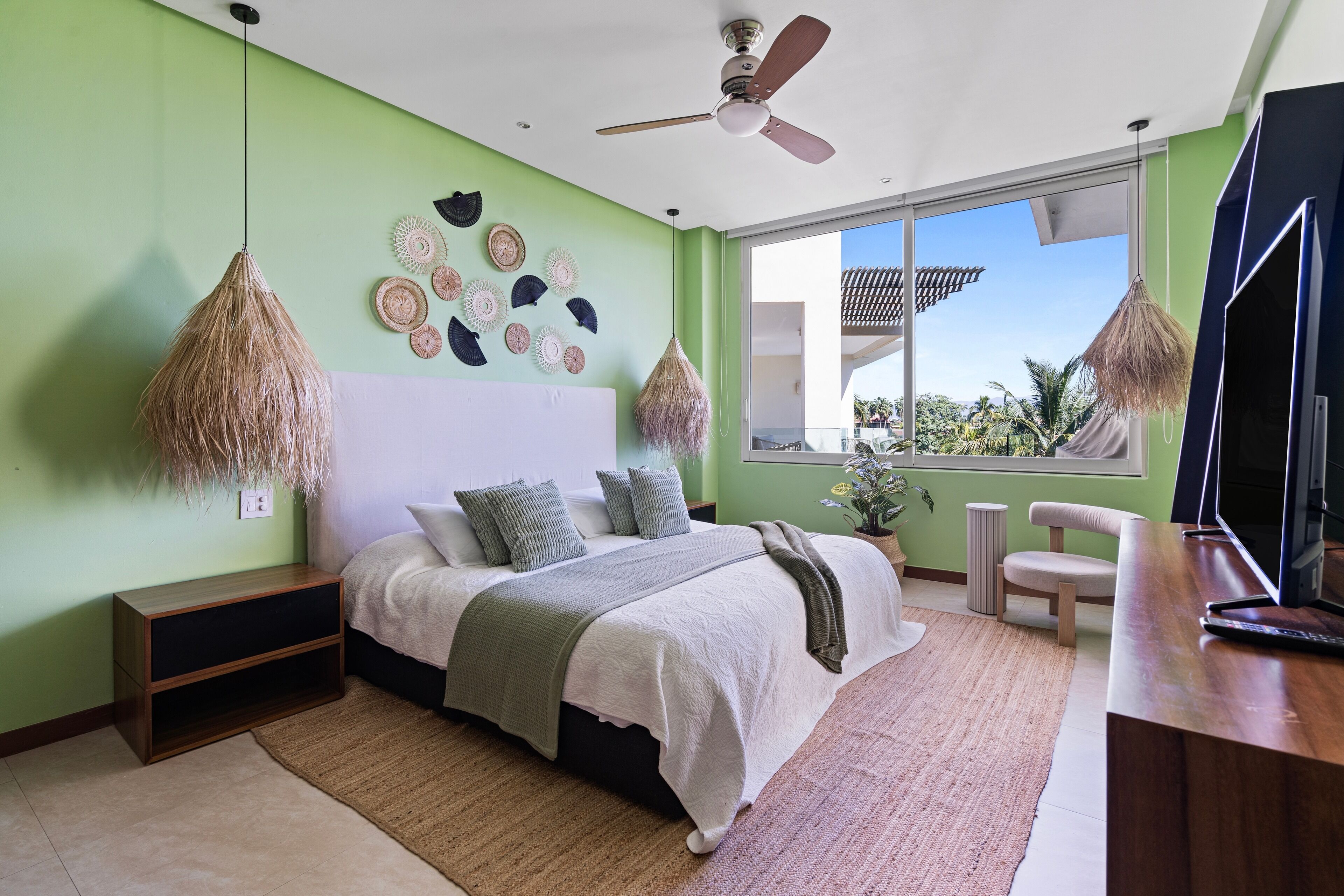 A modern bedroom with a bed, bedside tables, a desk, and a large window.