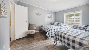 Une chambre avec deux lits, une chaise, une porte, un luminaire fixé au mur et une fenêtre avec des stores.