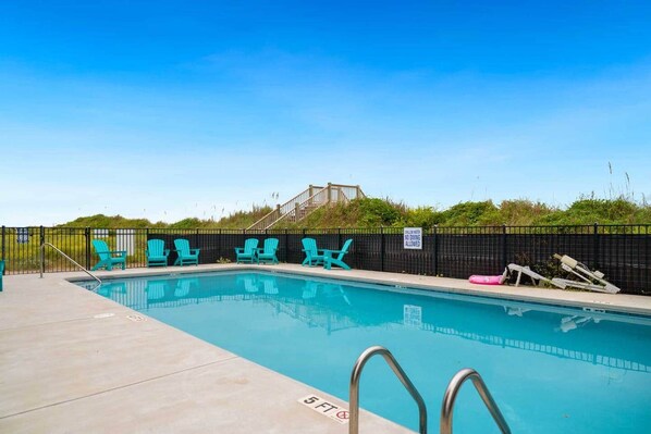 A swimming pool with a black fence, turquoise chairs, and a sign indicating no diving allowed.