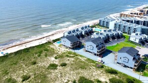 A coastal residential area with modern buildings, a beach, and a swimming pool.