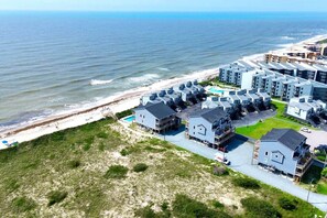 A coastal residential area with modern buildings, a beach, and a swimming pool.