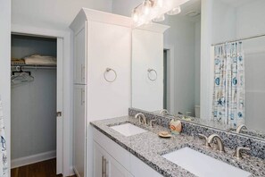 Un baño con dos lavamanos, un espejo grande y una cortina de ducha con motivos náuticos.