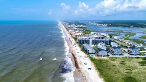 An aerial view of a coastal residential area with beachfront properties, a beach, and a marina.
