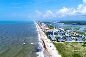 An aerial view of a coastal residential area with beachfront properties, a beach, and a marina.