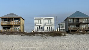 Una propiedad frente a la playa con una construcción de dos pisos, balcones y techo plano.