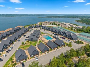 A residential area with multiple houses, a swimming pool, and a body of water in the background. - Cozy Branson Escape w/ Pool Access, Pvt Hot Tub , & Small-Dog Friendly (Hollister)