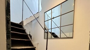 Una escalera de madera con barandilla de metal que conduce a un rellano con un amplio ventanal.