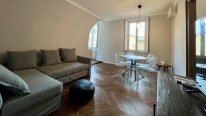 Amplia sala de estar con sofá, reposapiés, mesa de comedor y sillas.