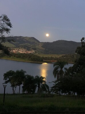 A lake with a reflection of the moon, surrounded by hills and trees. - Pousada Solar dos Sonhos (Joanópolis)