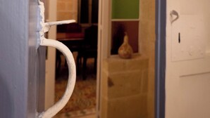 A doorway leading to a room with a chandelier, a tiled floor, and a brick wall. - SurWig Vacation Townhouse (Kerċem)