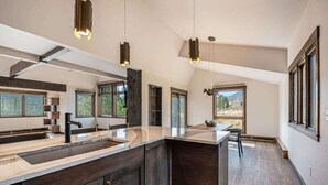 A modern kitchen with dark wood cabinets, a large island, and pendant lighting.