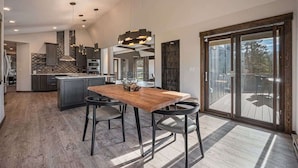 A spacious kitchen with a central island, modern pendant lighting, and a large sliding glass door leading to an outdoor deck.
