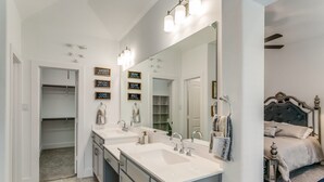 A modern bathroom with a large mirror, two sinks, and a walk-in closet. - Home away from home  (Lewisville)