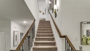 A staircase with carpeted steps, wooden handrails, and wall-mounted light fixtures. - Home away from home  (Lewisville)