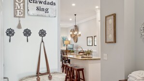 A hallway with a wooden floor, a door, and a wall with a 'Welcome' sign and a 'Crawdads Sing' sign. - Marsh & River Views, Large Screen Porch, Community Pool & Dock - Crawdads Sing (Folly Beach)