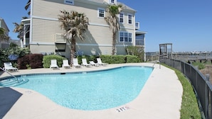 A swimming pool with a 3 FT depth marker, surrounded by lounge chairs and palm trees, with a building in the background. - Marsh & River Views, Large Screen Porch, Community Pool & Dock - Crawdads Sing (Folly Beach)