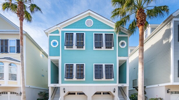A two-story house with a blue exterior, white trim, and a front entrance with a staircase. - Marsh & River Views, Large Screen Porch, Community Pool & Dock - Crawdads Sing (Folly Beach)