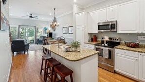A modern kitchen with white cabinets, granite countertops, and stainless steel appliances. - Marsh & River Views, Large Screen Porch, Community Pool & Dock - Crawdads Sing (Folly Beach)