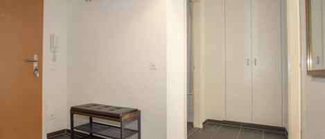 Un pasillo con un banco, una puerta de madera y un armario blanco.