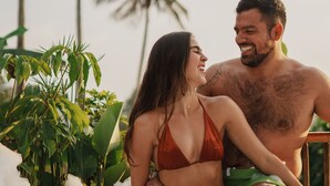 Een koppel ontspant in een jacuzzi, omringd door tropische planten en palmbomen.