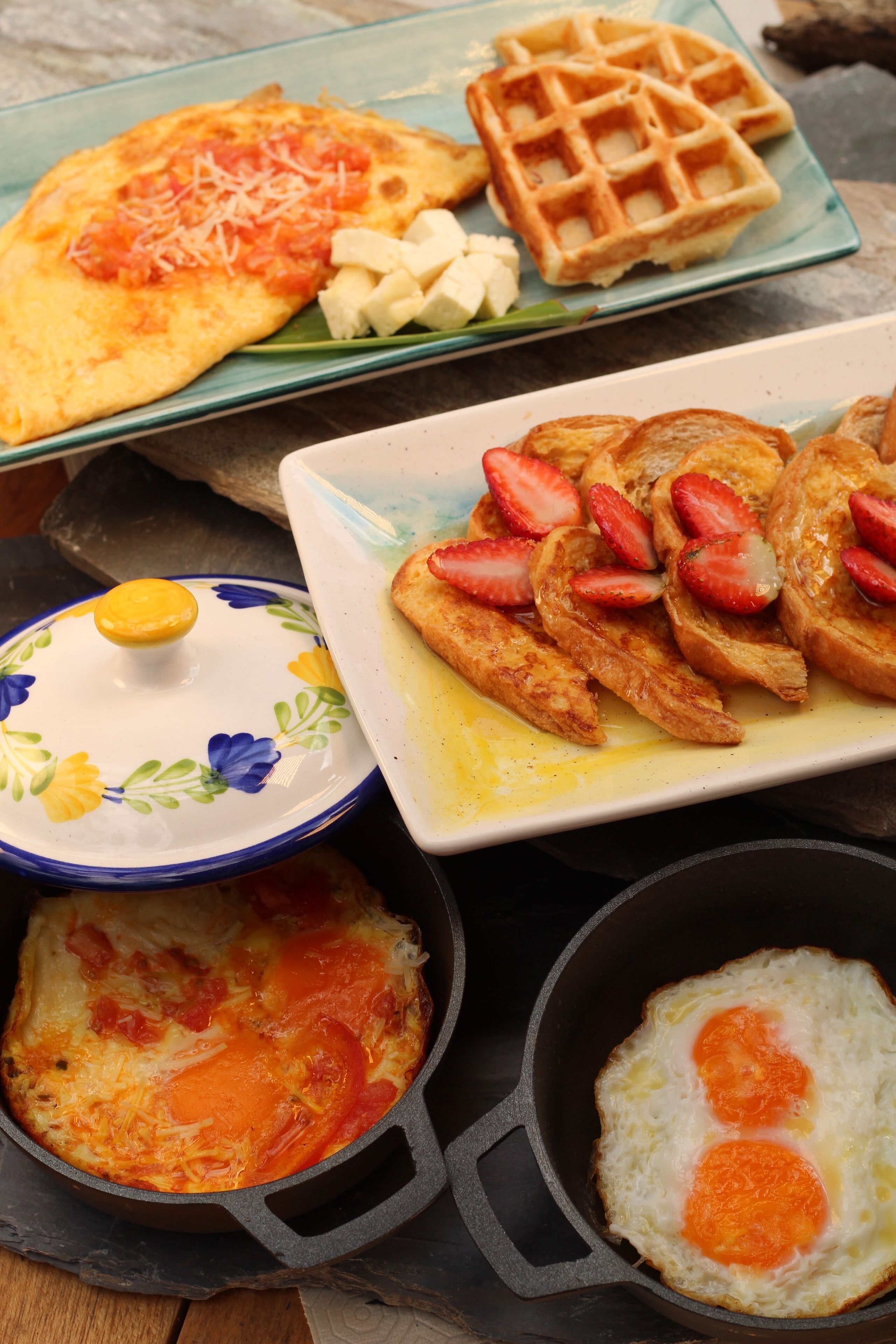 A breakfast plate with waffles, scrambled eggs, and toast with strawberries.