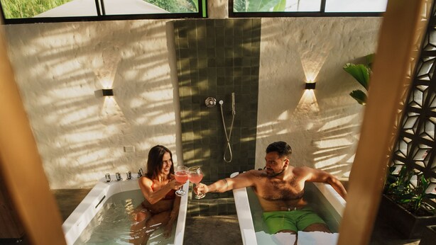 Twee aparte badkuipen in een wellnessruimte met uitzicht op groen.