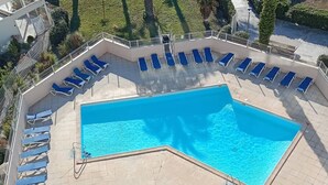 Ein Pool auf dem Dach mit blauem Wasser, umgeben von Liegestühlen und einer gefliesten Terrasse.