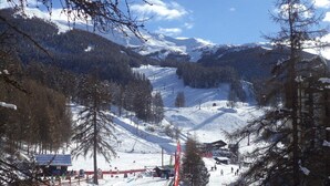 Un paysage de montagne enneigé avec des pistes de ski, un télésiège et un petit chalet.