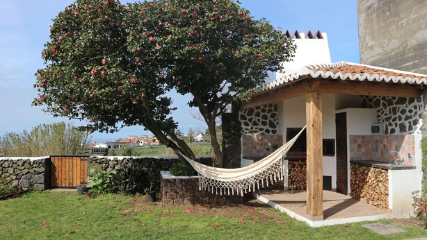 Una casa con muro de piedra, una hamaca y vista al mar.