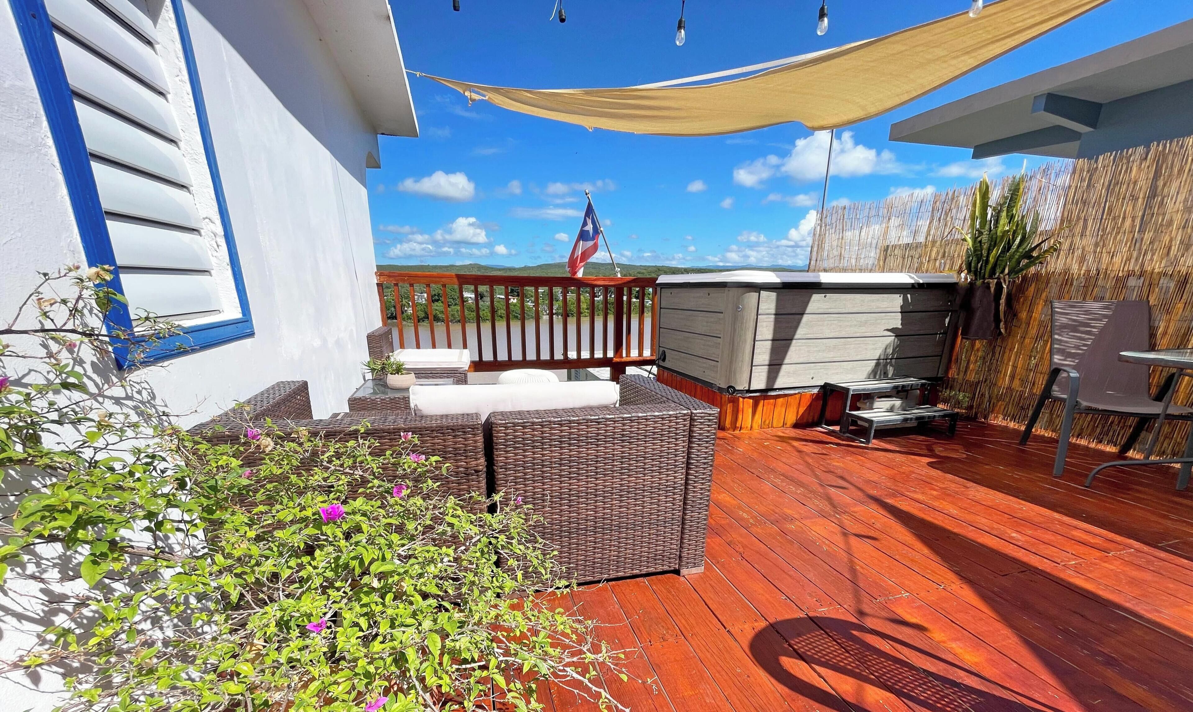 A wooden deck with wicker furniture, a patio umbrella, and a view of a mountain range.