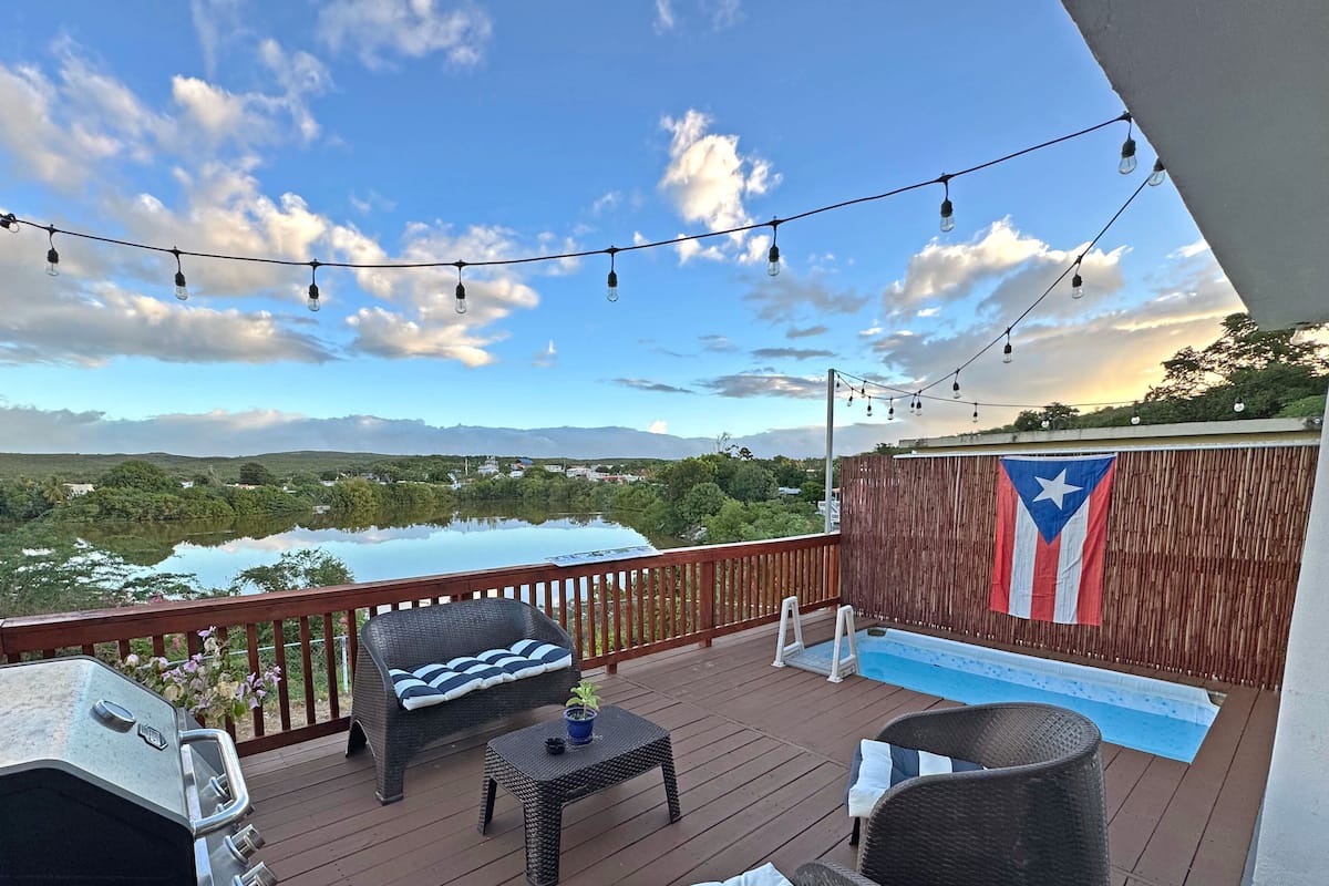 Une terrasse dotée de mobilier d’extérieur, d’un barbecue, d’une petite table avec une plante et d’un drapeau.