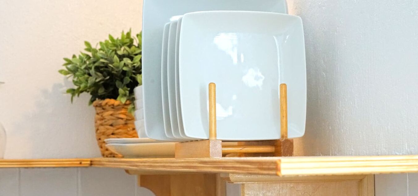 A set of white plates with gold handles on a wooden stand.