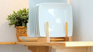 A set of white plates with gold handles on a wooden stand.