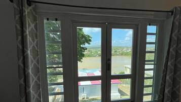 A bay window with a view of a river and distant buildings.