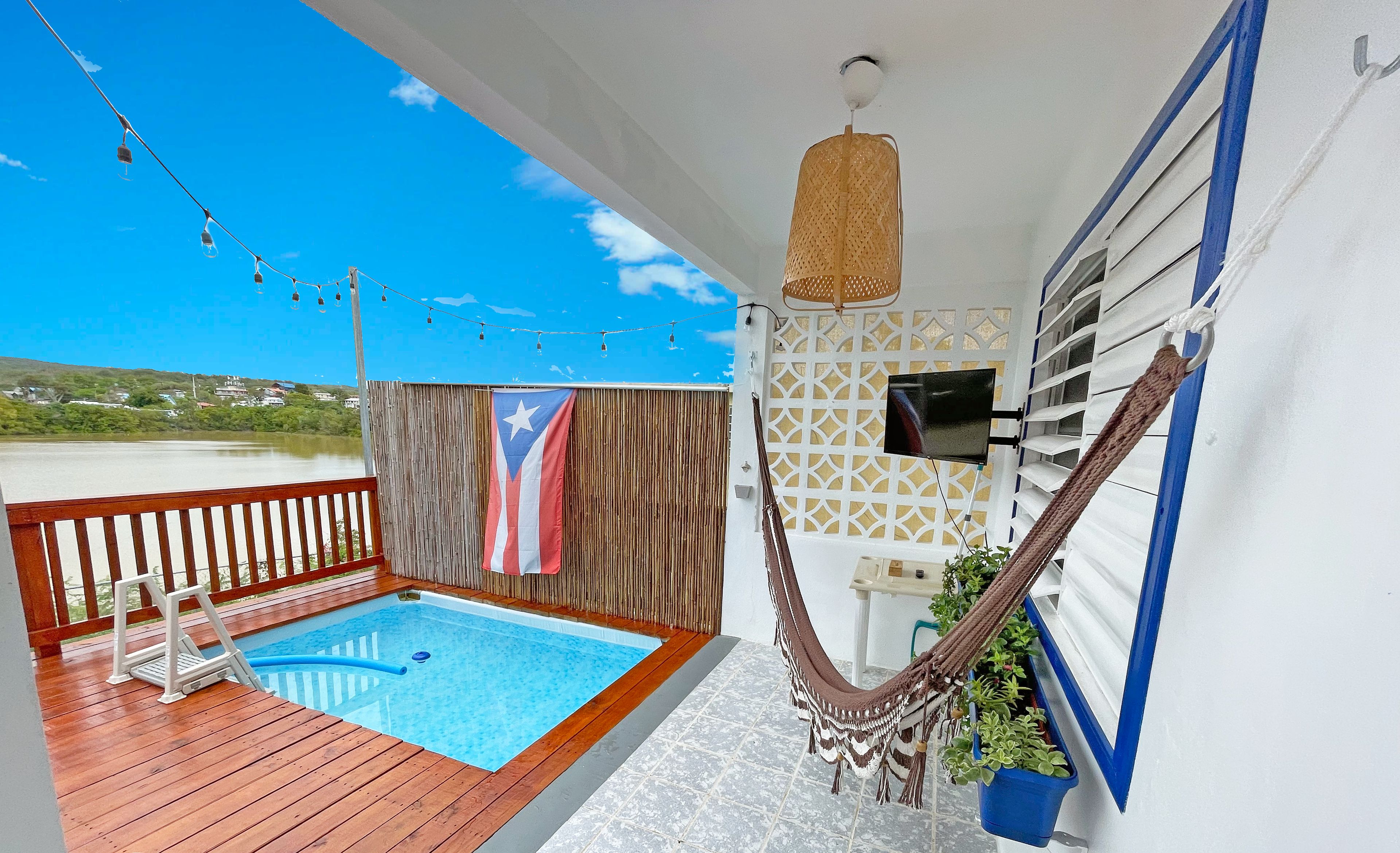 A pool area with a wooden deck, a hammock, and a flag.