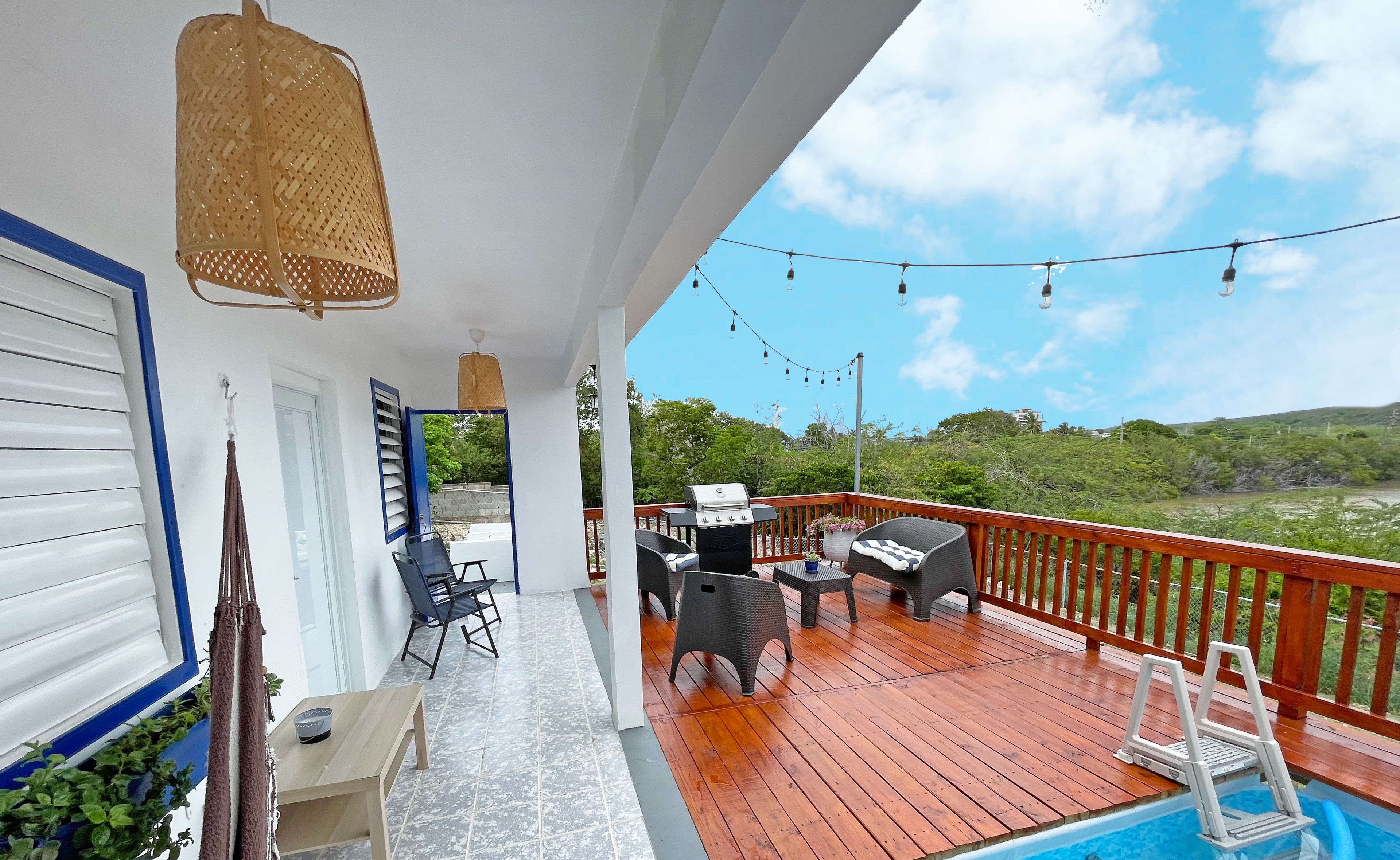 A covered outdoor area with a pool, wooden deck, and outdoor furniture.