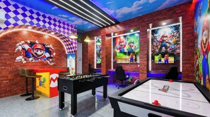 Ett rum med ett fotbollsspel, en vägg dekorerad med motiv från Mario och en vägg med ett murstensmönster.