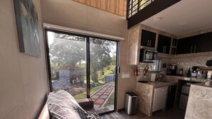 A modern kitchen with a large window, a sofa with a blanket, and a trash bin. - Villazul 2 (Sabana Redonda)