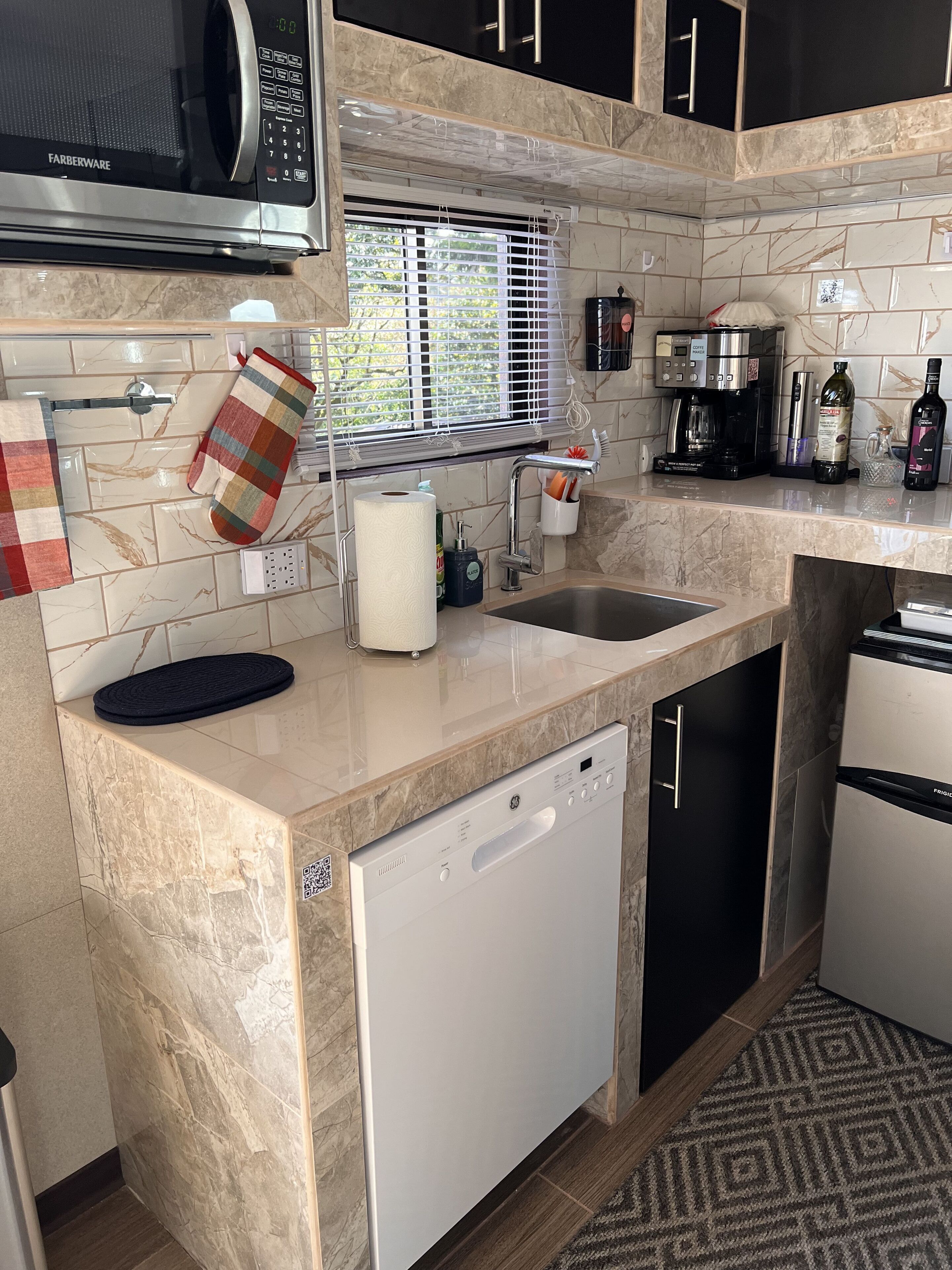 A modern kitchen with a dishwasher, a coffee maker, and a refrigerator.