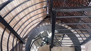 A spiral staircase with a black metal railing and a wooden floor. - Villazul 2 (Sabana Redonda)