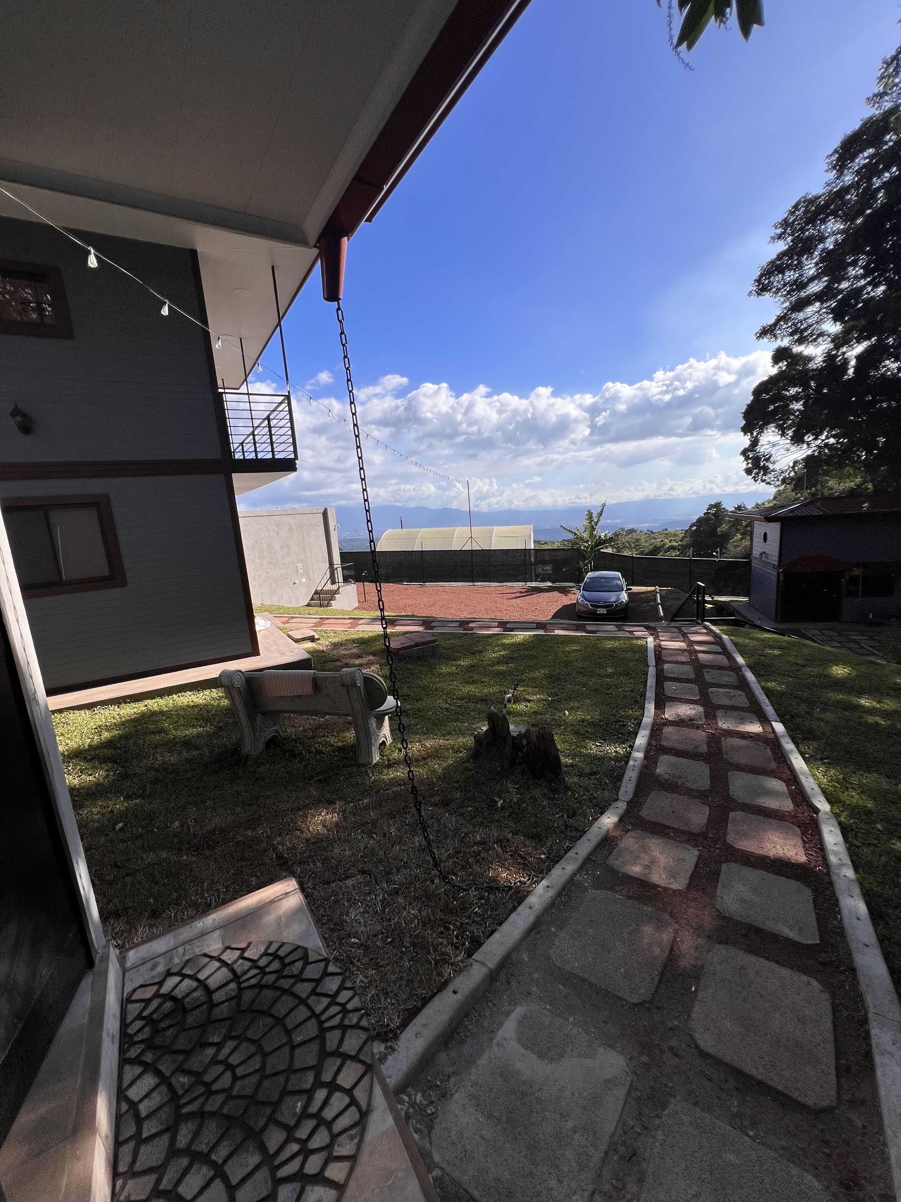 A residential area with a paved pathway leading to a car parked in the distance.