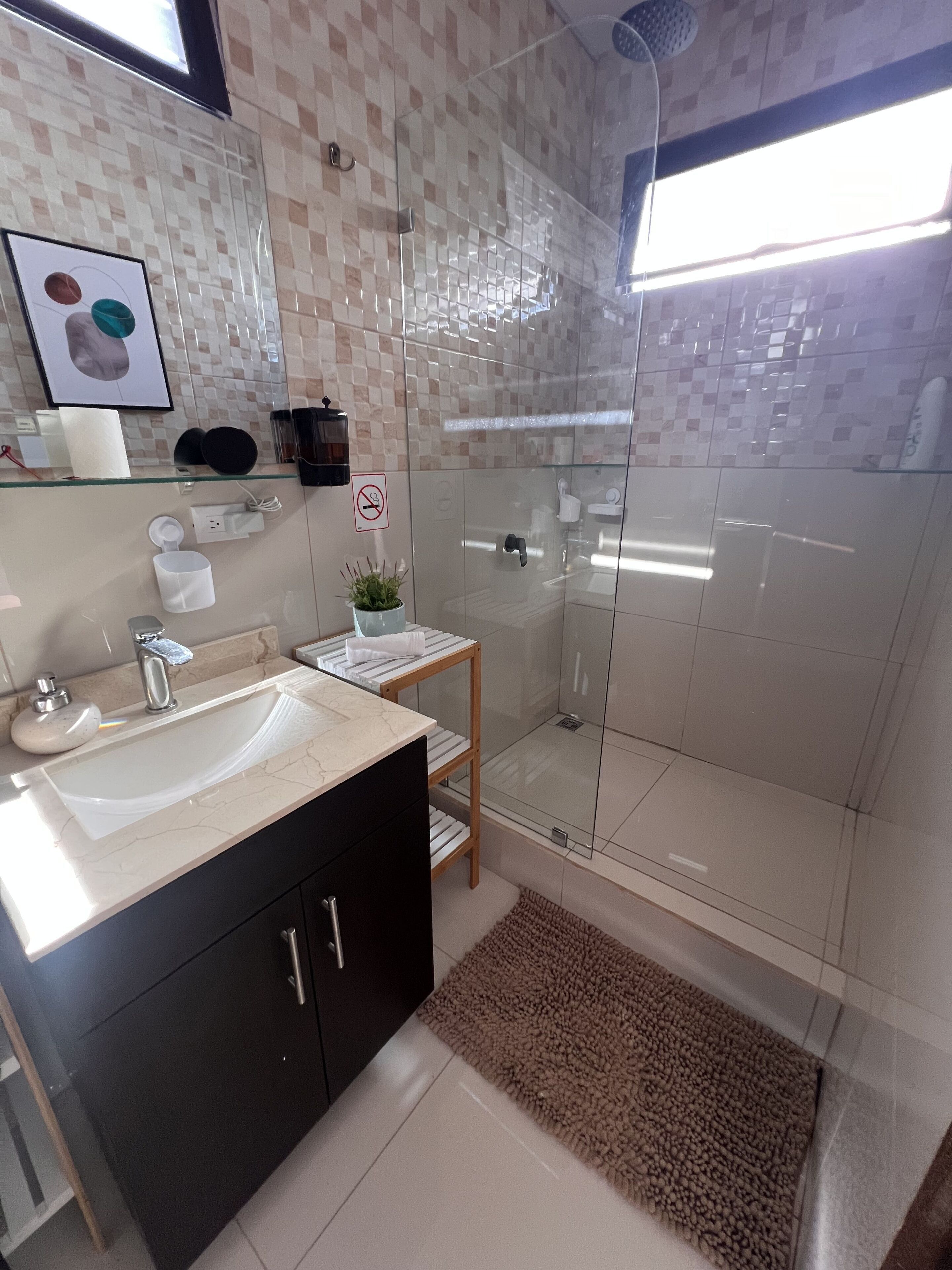 A modern bathroom with a glass-enclosed shower, a vanity with a sink, and a mirror.