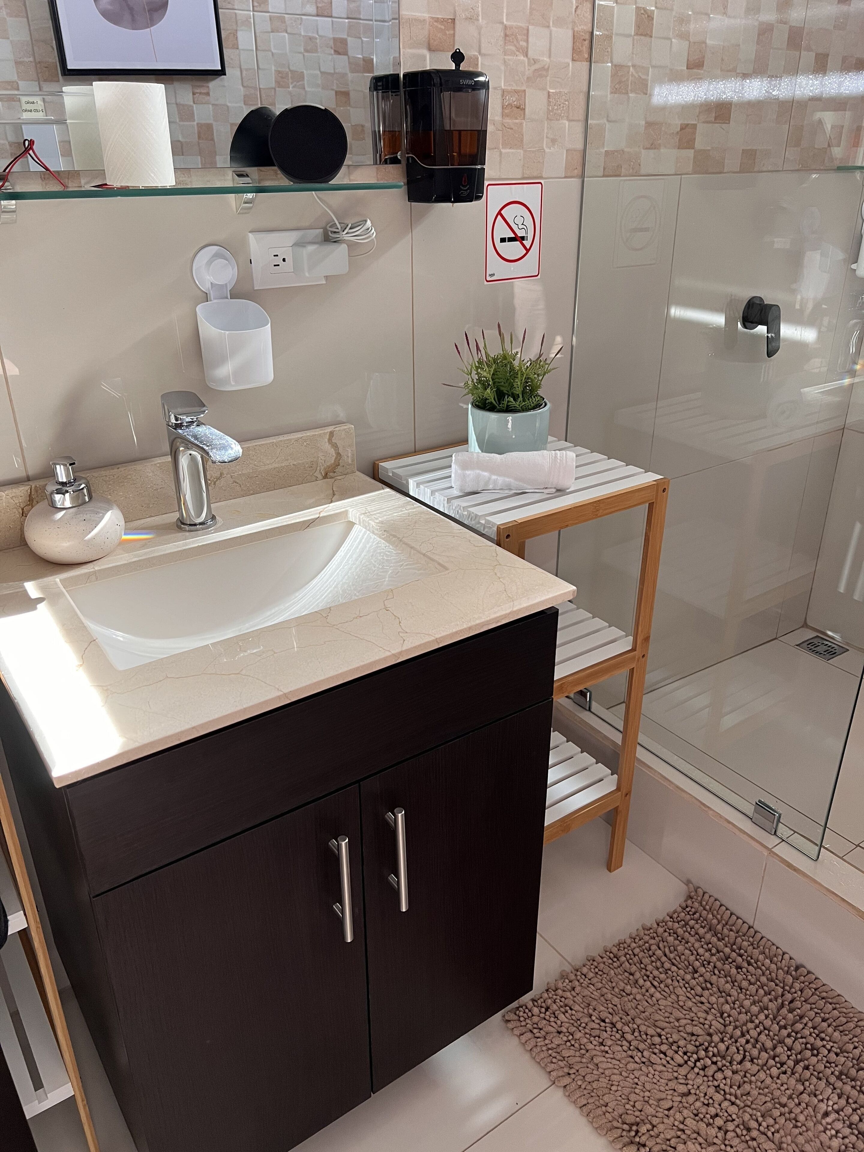A modern bathroom with a sink, mirror, and a glass shower enclosure.